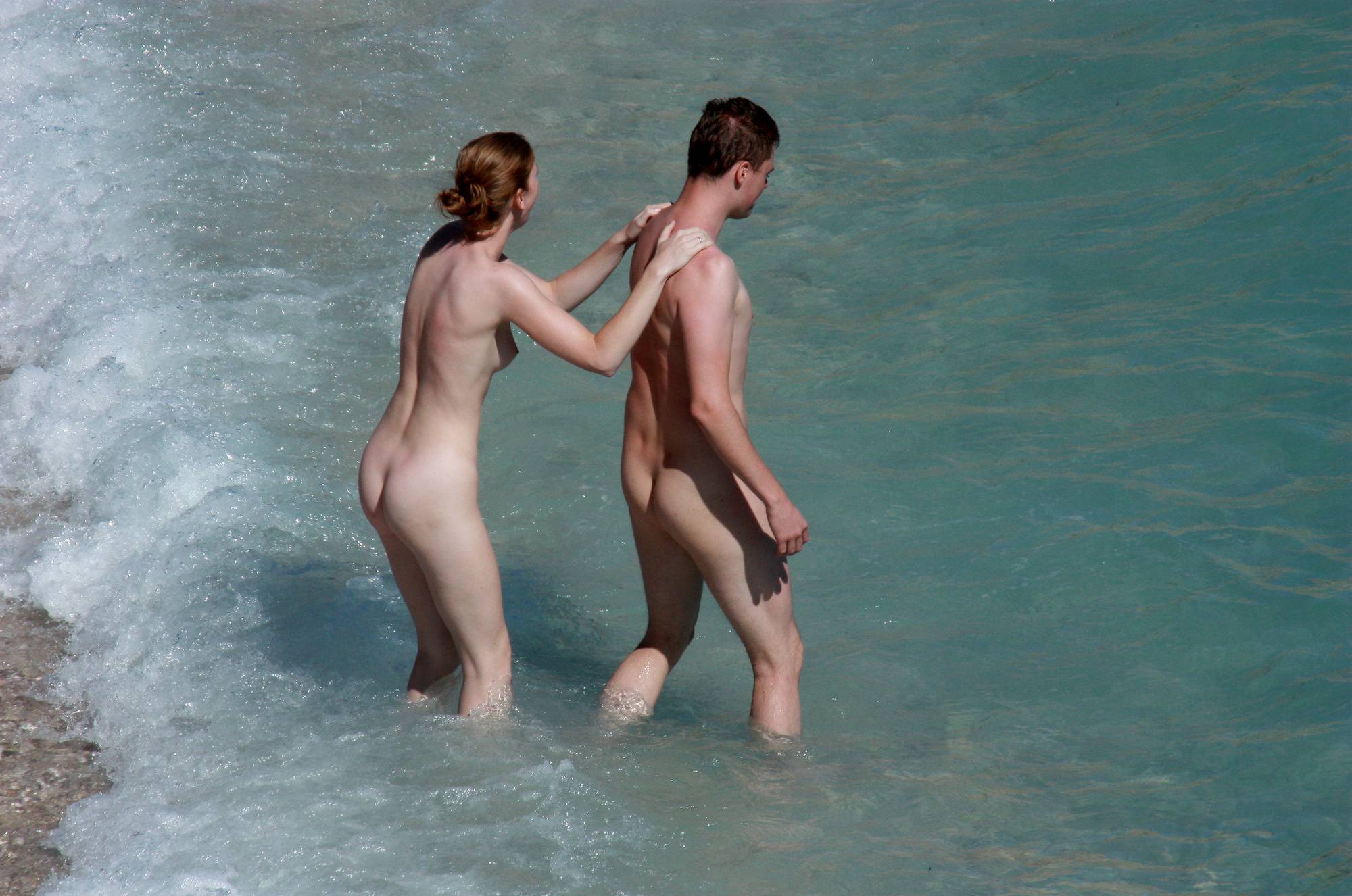 Family nudism at its finest: A young nudist couple enjoying the the sea