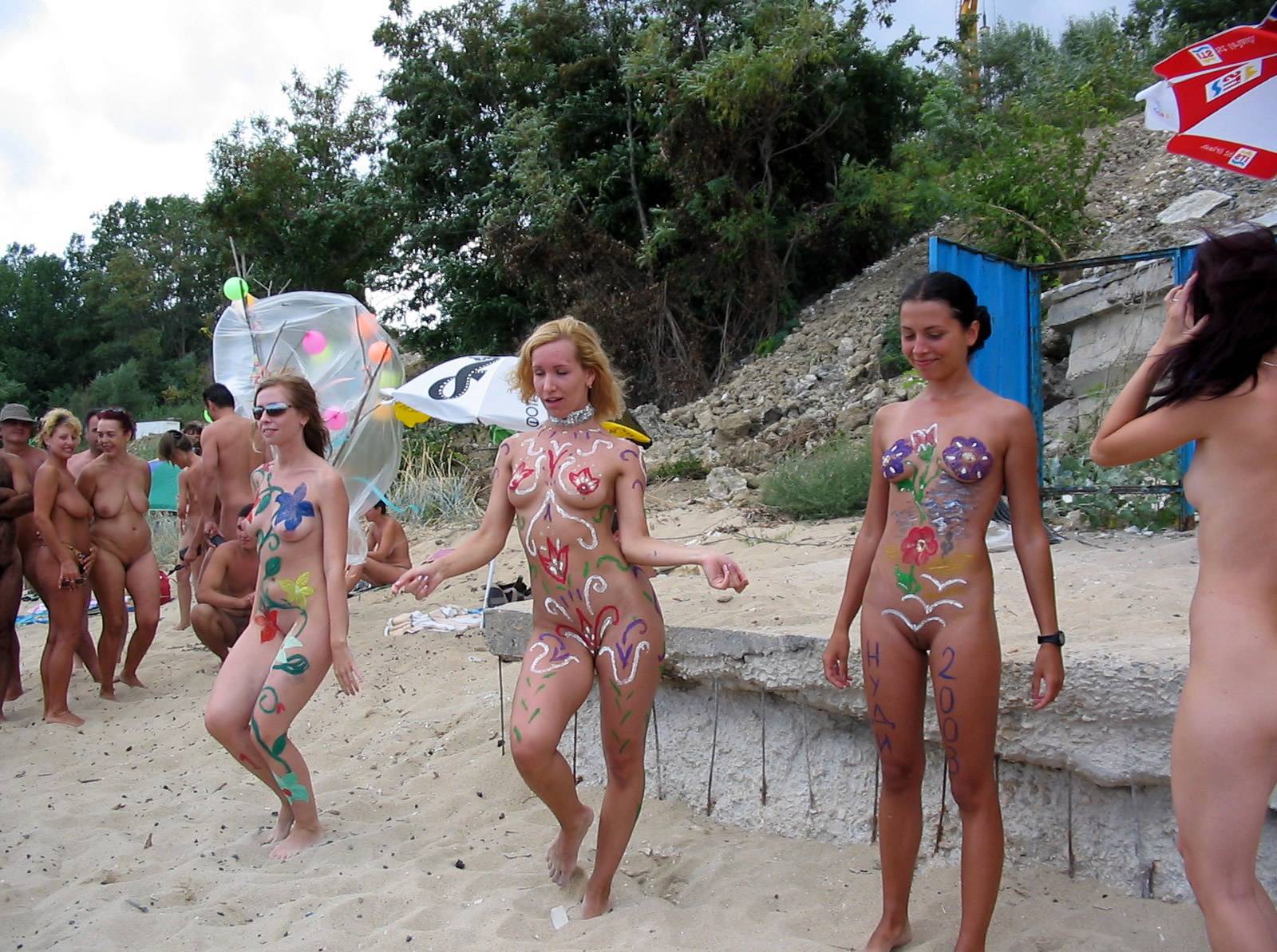 Vibrant expression of naturism: Women adorned with captivating body painting, dancing on the sand